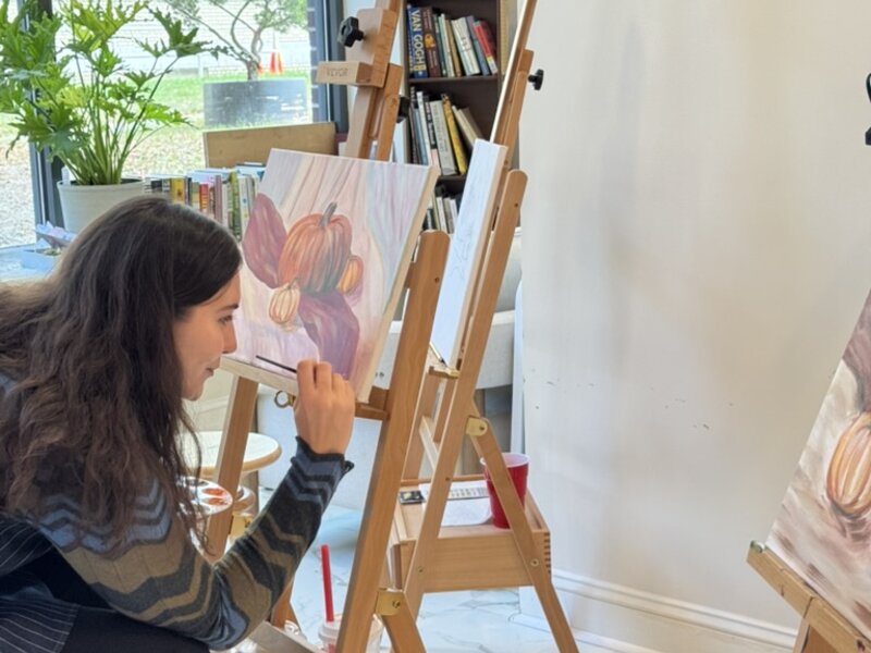 Artist painting pumpkins beside a studio window