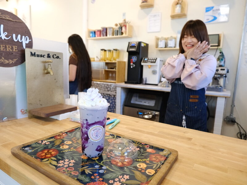 Purple boba drink on a floral tray at the Muse & Co counter